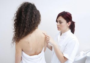 dermatologist doctor inspecting woman skin for moles and melanoma